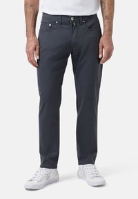 Pantalon en coton gris avec une coupe slim, design à cinq poches et coutures contrastées. Accompagné de baskets blanches.