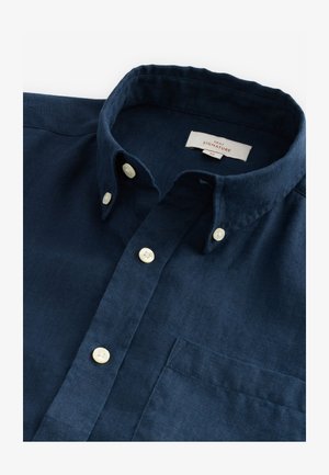 Camicia in lino blu navy con colletto button-down, bottoni bianchi e taschino sul petto. Presenta un tessuto strutturato per un dettaglio aggiuntivo.