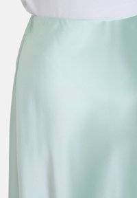 Jupe en satin vert menthe avec une texture lisse, arborant un design simple et une taille élastique pour un ajustement confortable.