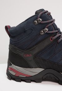 Wanderschuh mit Obermaterial aus marineblauem Wildleder und Mesh, schwarzen synthetischen Akzenten, roten Details und einer robusten Laufsohle für gute Traktion.