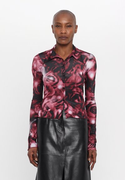Blouse à manches longues avec un imprimé floral dans des tons de rouge et de noir, dotée d'un col, d'une fermeture à boutons et d'une coupe ajustée.