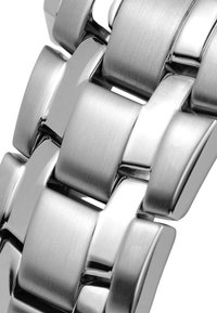 Sidabro nerūdijančio plieno laikrodžio apyrankė su persidengiančiais ryšiais, turinti šlifuotą ir blizgų paviršių, sukuriantį tekstūruotą išvaizdą.