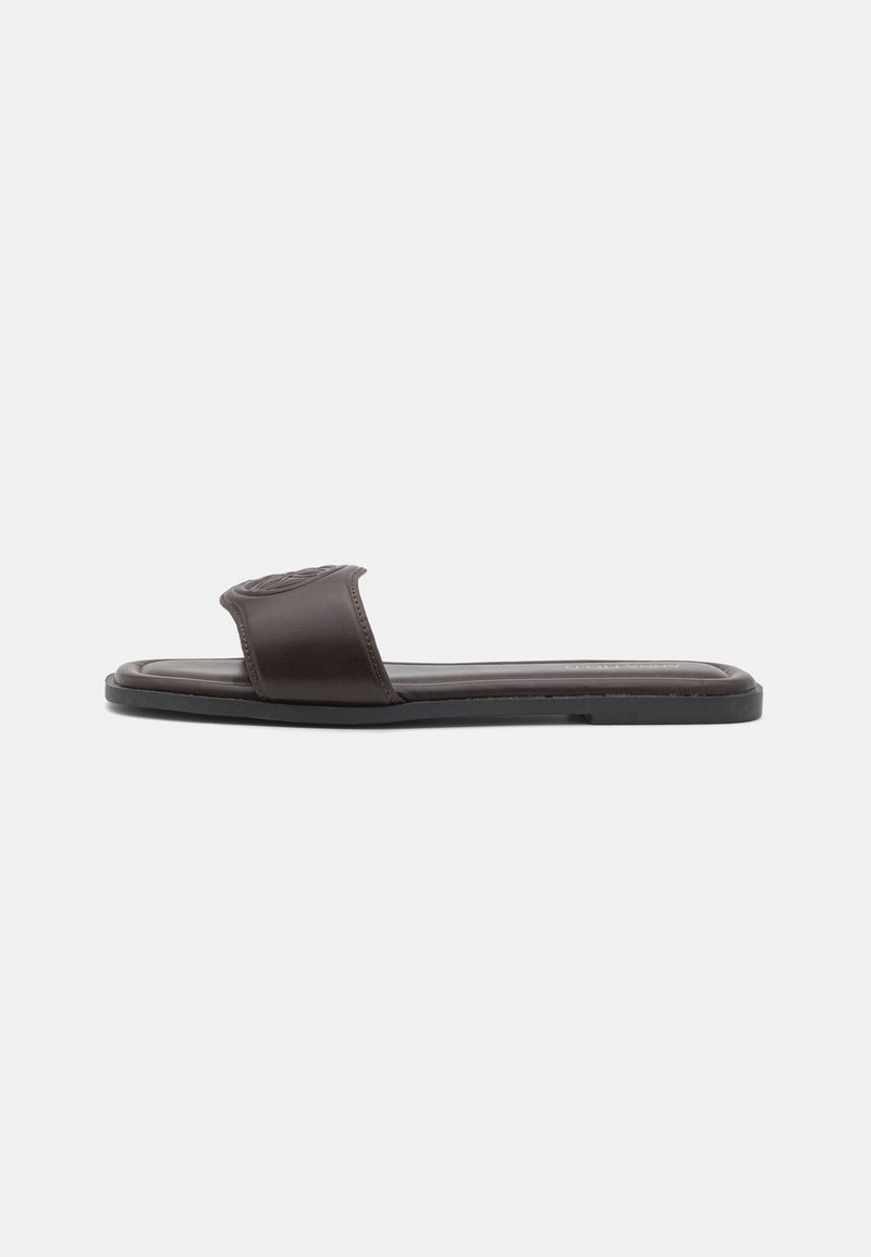 Bruna lädersandaler med bred rem och texturmönster. Platt sula med slät yta, minimalistisk design.