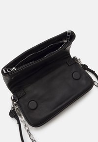 Zwarte leren tas met een gladde textuur, ritssluiting en kettingband. Binnenin heeft de tas een ruime compartiment en twee ronde hardwaredetails.