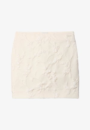 Minirok in crèmekleur met subtiele verhoogde bloemenborduursel en een klein metalen merkteken aan de rechterbovenkant.