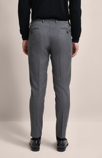 Graue maßgeschneiderte Hosen mit glatter Textur, zwei Gesäßtaschen und einem Slim-Fit-Schnitt. Kombiniert mit schwarzen Schuhen und einem Pullover.