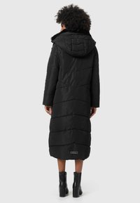 Manteau d'hiver noir, long, avec une capuche, présentant un design matelassé et des poches latérales. Accentué par une étiquette logo à l'ourlet.