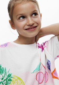 Vit bomulls-T-shirt med rund halsringning som har färgglada fruktskisser i grönt, rosa, blått och orange. Mjuk textur, avslappnad passform.