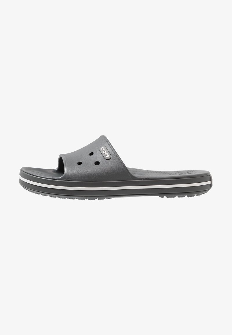 Sandale slide unique gris foncé avec des trous de ventilation et une bande blanche le long de la semelle épaisse, marquée d'un petit logo sur la bride supérieure.