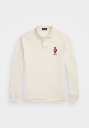 Camisa polo de manga larga en algodón color crema, con una tapeta de tres botones, puños acanalados y un logotipo bordado en el lado izquierdo del pecho.