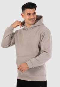 Lichtgrijze hoodie van zachte stof, met een voorzak, ribgebreide boorden en een capuchon met trekkoord en een klein logo-detail.
