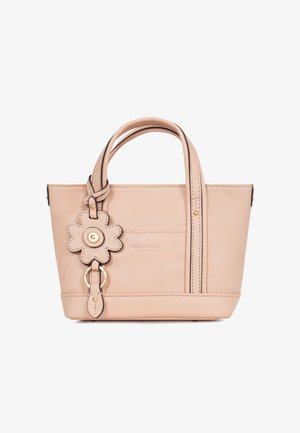 Kleine beige leren handtas met dubbele handvatten en een bloemvormige lederen hanger die aan één handvat hangt.