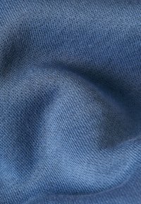 Tissu bleu clair, texturé, avec un motif de tricot fin, présentant des variations subtiles dans le tissage et la couleur pour créer de la profondeur et de la dimension.