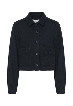 Musta lyhyt takki, jossa on tekstuuri, varustettuna kauluksellisella kauluksella, napilla edessä ja kahdella rintataskulla, joissa on fringed yksityiskohtia.