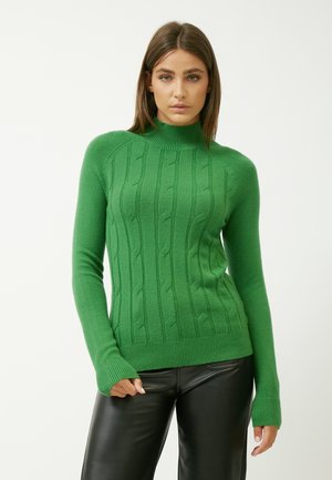 Maglione verde a maglia con collo alto, caratterizzato da un motivo a treccia e orlo a costine. Morbido al tatto; maniche aderenti con aperture per i pollici.