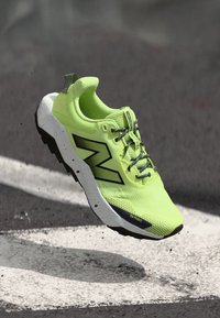 Running shoe in bright neon yellow with black accents. Features a textured surface, lightweight materials, and reinforced toe protection.