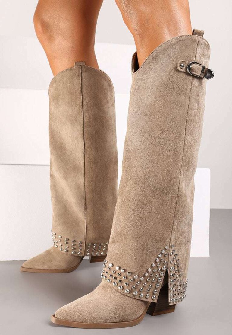 Bottes en suede beige jusqu'aux genoux avec des pointes, ornées de clous en argent au niveau des revers, dotées d'une boucle sur le côté pour l'ajustement.