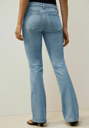 Light blue denim flared jeans with a fitted waistband, five-pocket design, and subtle texture; slightly distressed appearance on the fabric.