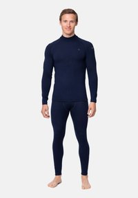 Navyblauwe thermische basislaag set, met een hoge kraag en lange mouwen, gemaakt van gestructureerd, aansluitend materiaal, gedragen met blote voeten.