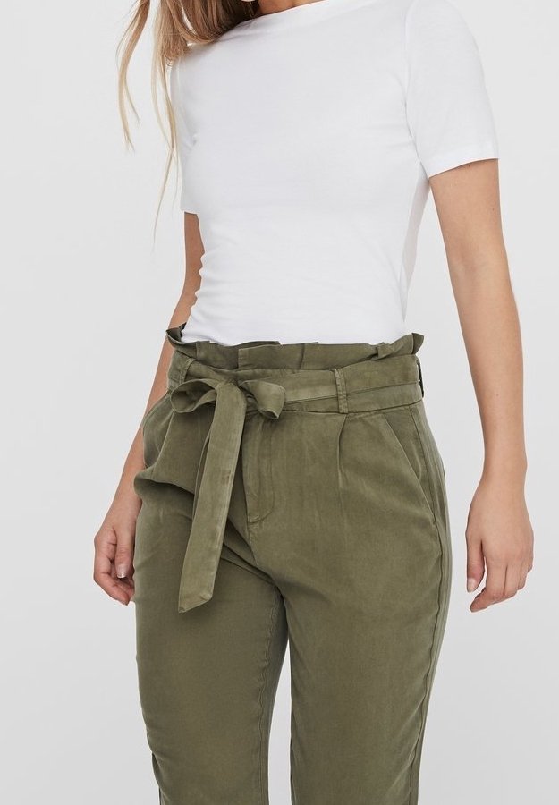 Haut blanc ajusté à manches courtes associé à un pantalon taille haute vert olive, avec une ceinture en tissu nouée et des poches latérales. Texture douce.
