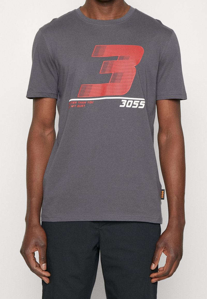 Graues Baumwoll-T-Shirt mit einer großen roten Zahl "3" und dem weißen Text "3055", mit glatter Textur und Rundhalsausschnitt.