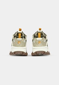 Zapatillas deportivas verdes y beige con paneles de malla, suelas de goma y tiradores naranjas en el talón. Presentan acentos reflectantes y superficies texturizadas.