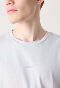 Light gray crew-neck t-shirt made of smooth fabric, featuring a subtle, embossed "BOSS" logo in a matching shade on the chest.