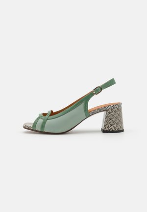 Groene leren slingback sandaal met open neus, decoratieve voorbanden, een gouden gesp en een zwart-wit gestreepte blokhak.