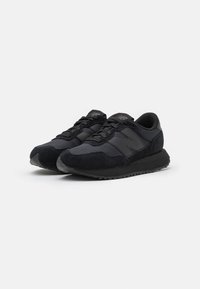 Schwarze sportliche Sneakers aus Wildleder und synthetischen Materialien; besitzen ein low-profile Design mit einer strukturierten Sohle und tonalem Branding.