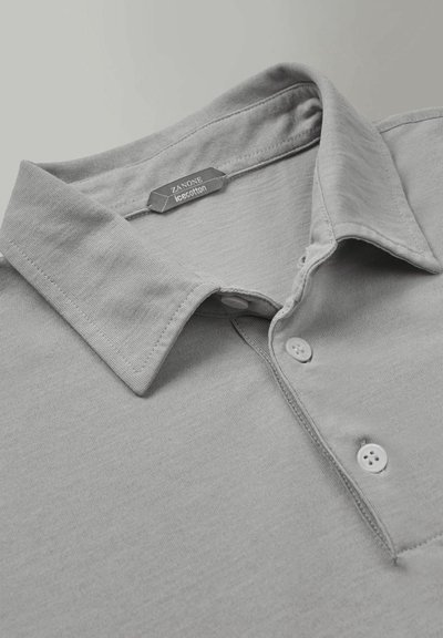 Grijze polo gemaakt van ice cotton, met een opgevouwen kraag, een knoopsluiting met drie knopen en een label met de merknaam zichtbaar.