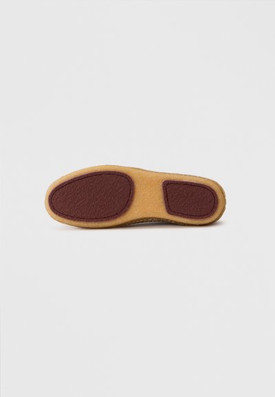 Semelle d'une chaussure avec une base en caoutchouc lisse de couleur beige et un accent texturé marron, de forme arrondie et au design flexible.