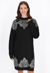 Zwart gebreid jurkje met een losse pasvorm, lange mouwen en metallic zilveren kantachtige details op de schouders en zoom.