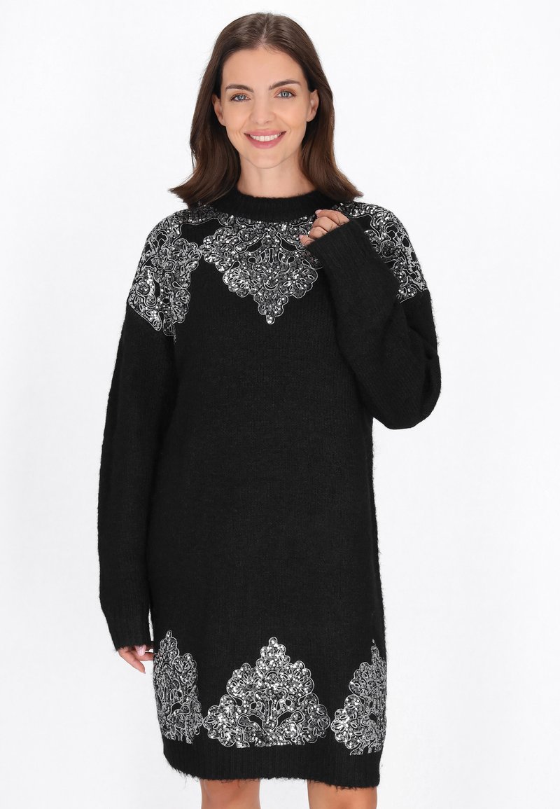 Zwart gebreid jurkje met een losse pasvorm, lange mouwen en metallic zilveren kantachtige details op de schouders en zoom.