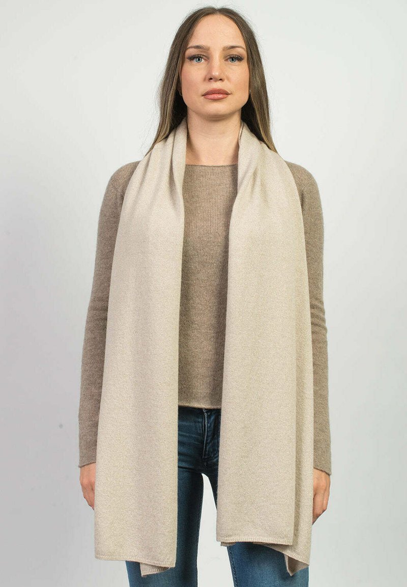 Beige tørklæde lavet af blødt, tekstureret stof, der er draperet omkring bærerens hals, med rene kanter og et flydende design.