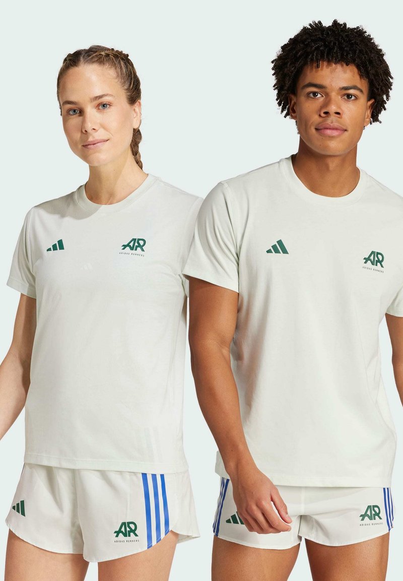Lystgrønne atletiske T-shirts med grønne logoer og tre-stribede accenter. Komplementerende hvide shorts har blå striber og grøn branding.