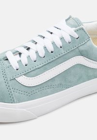 Baskets en daim de couleur bleu sarcelle clair avec des lacets blancs et une bande latérale blanche distinctive. Tige texturée avec une semelle en caoutchouc.