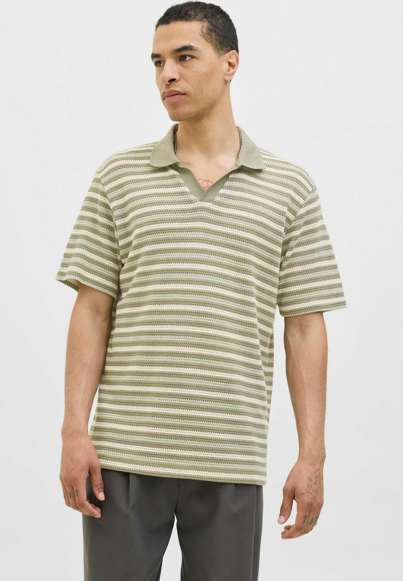 Kortærmet polo-shirt med V-hals, stribet mønster i lysegrøn og creme, lavet af tekstureret stof.