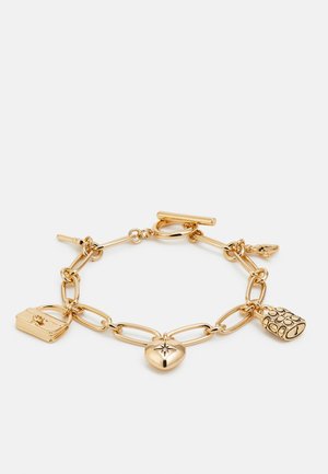 Pulsera de cadena de oro con grandes eslabones y tres colgantes: un corazón, un bolso y un charm redondo texturizado con detalles.