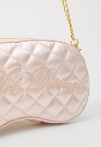 Kvalitná saténová ružová kabelka s prešívaným vzorom a zlatým reťazovým popruhom, s embosovaným textom "Nerušit" na jednej strane. Mäkka textúra a zaoblený tvar.