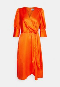 Robe portefeuille en satin orange avec manches bouffantes, motif à pois, encolure en V et ceinture nouée à la taille. Ourlet asymétrique.