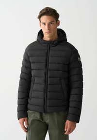 Melnā pūkains jaka ar horizontālām quilted rakstām, ar rāvējslēdzēju priekšpusē un kapuci. Ar sānu kabatām un logo uz kreisā roka. Gluda tekstūra.