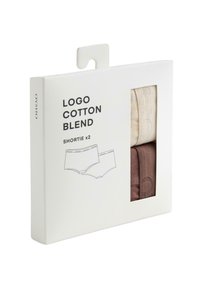 Deux culottes courtes en mélange de coton, en crème et marron, emballées dans une boîte blanche avec une découpe et un design de logo minimaliste.