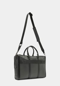 Schwarze Ledertasche mit zwei oberen Griffen, verstellbarem Schultergurt, Reißverschluss und dezentem, geprägtem Logo auf der Vorderseite.