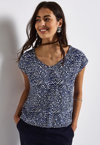 Top a righe blu e bianche con maniche corte, caratterizzato da un design a scollo a V e forme geometriche. Tessuto morbido con una vestibilità comoda.