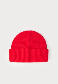 Red knitted beanie with a fold-over cuff. Features ribbed texture and a rounded top, made of soft, stretchy material.