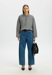 Hall hall polo-särk, pikkade varrukatega, lahtise istuvusega; kõrge vöökohaga sinised teksad; mustad teravaotsalised kontsakingad ja must kott mitmevärvilise aktsendiga.