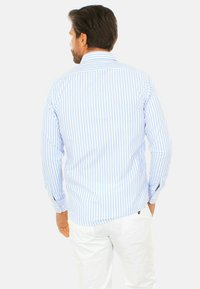 Camicia a maniche lunghe a righe blu chiaro e bianche con colletto a punta e maniche con polsino, realizzata in tessuto liscio.
