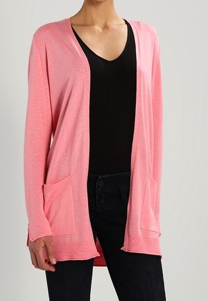 Cardigan rosa lavorato a maglia con apertura frontale, maniche lunghe e due tasche frontali. Texture morbida e vestibilità rilassata, abbinato a un top nero e jeans.