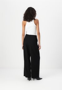 Black wide-leg trousers with a high waist, made from a smooth material. Features two back pockets and a subtle crease down the front.