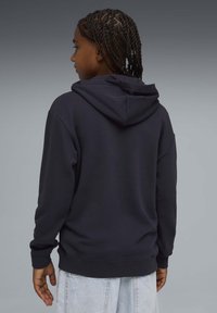 Sweat à capuche bleu marine à manches longues, texture douce, avec poignets côtelés. Design uni avec une coupe décontractée, vu de dos.